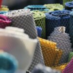 Vibrant mesh fabric rolls in various colors on display outdoors at the Mayen fabric market.