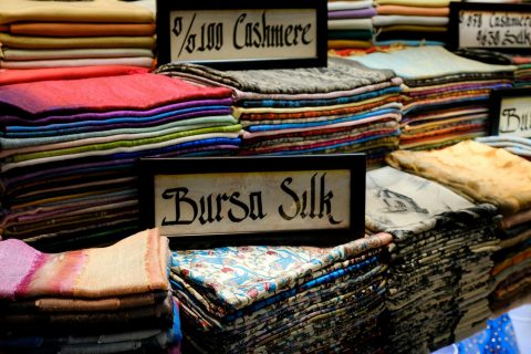 Vibrant stacked fabrics featuring cashmere and silk at a market stall.